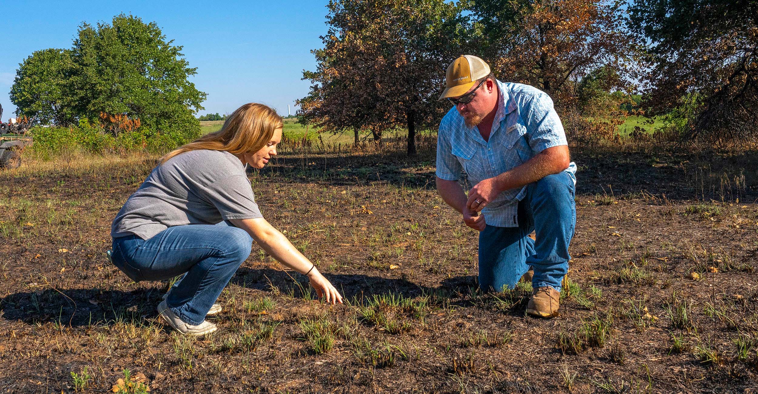 Hannah Baker and Cooper Sherill looking at burned grass.