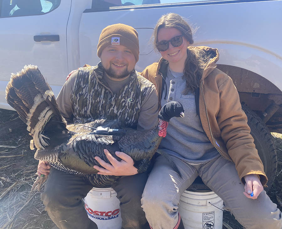 Students Mitchell Nagel, on the left, and Lydia Laughlin, pose while holding a wild turkey during their in-field research.