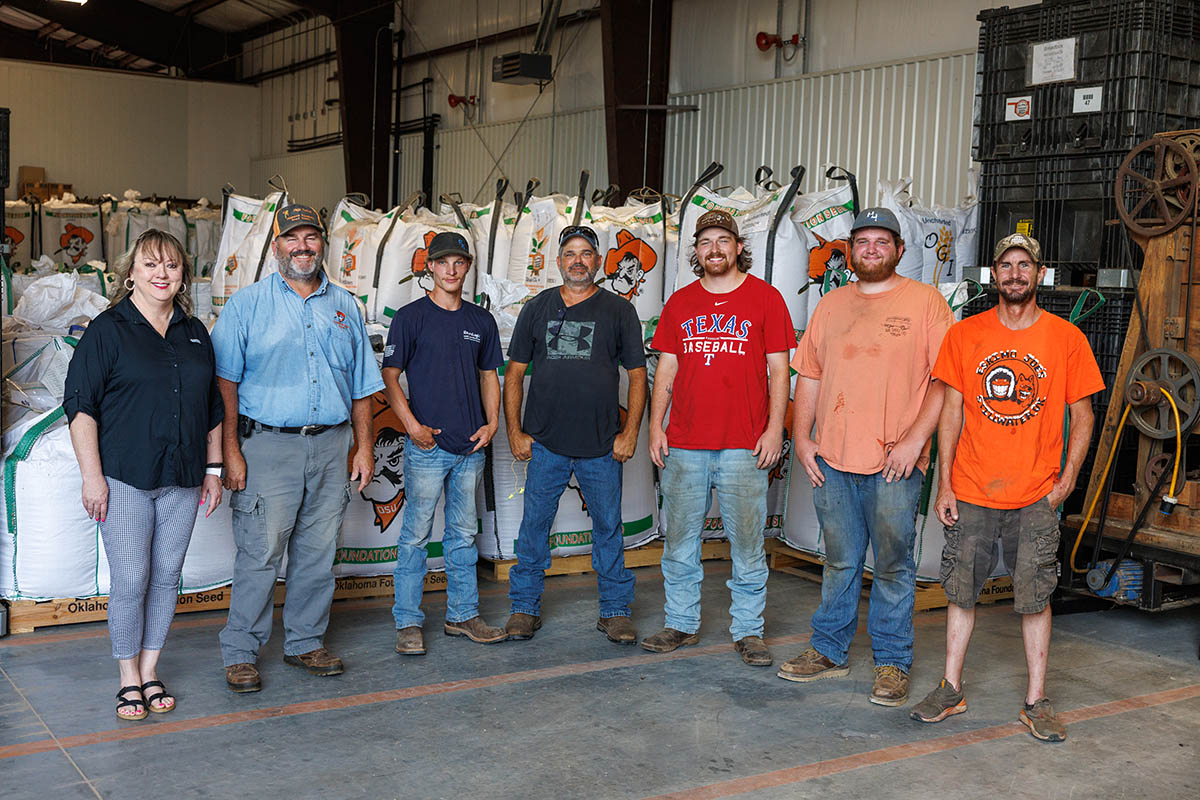The seven staff members posed in front of seed bags