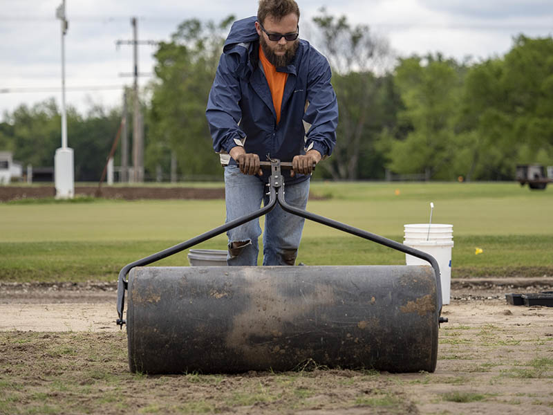 A graduate student flattening the turfgrass soil