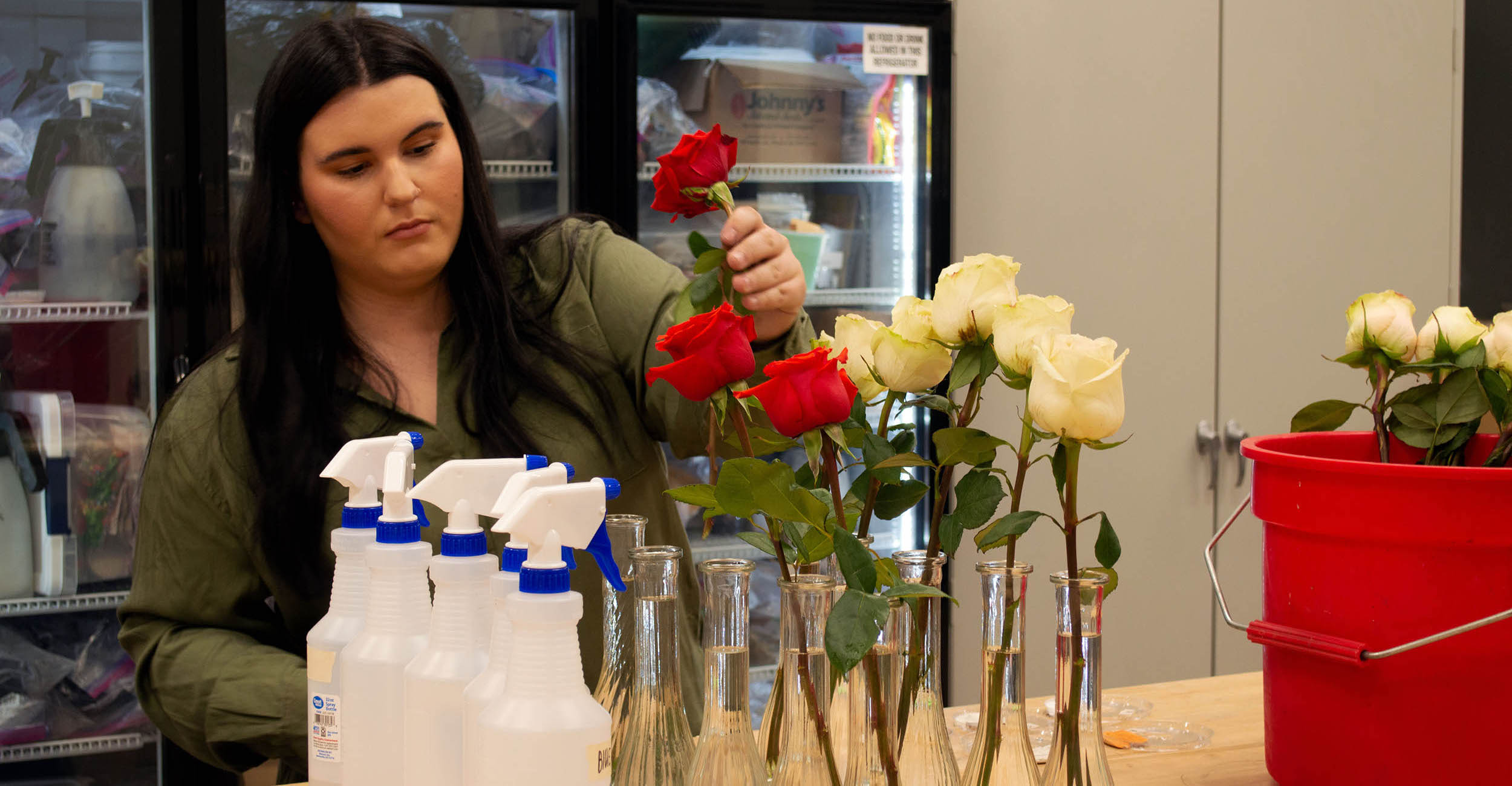 Abby Pace placing roses into vases on a counter top.