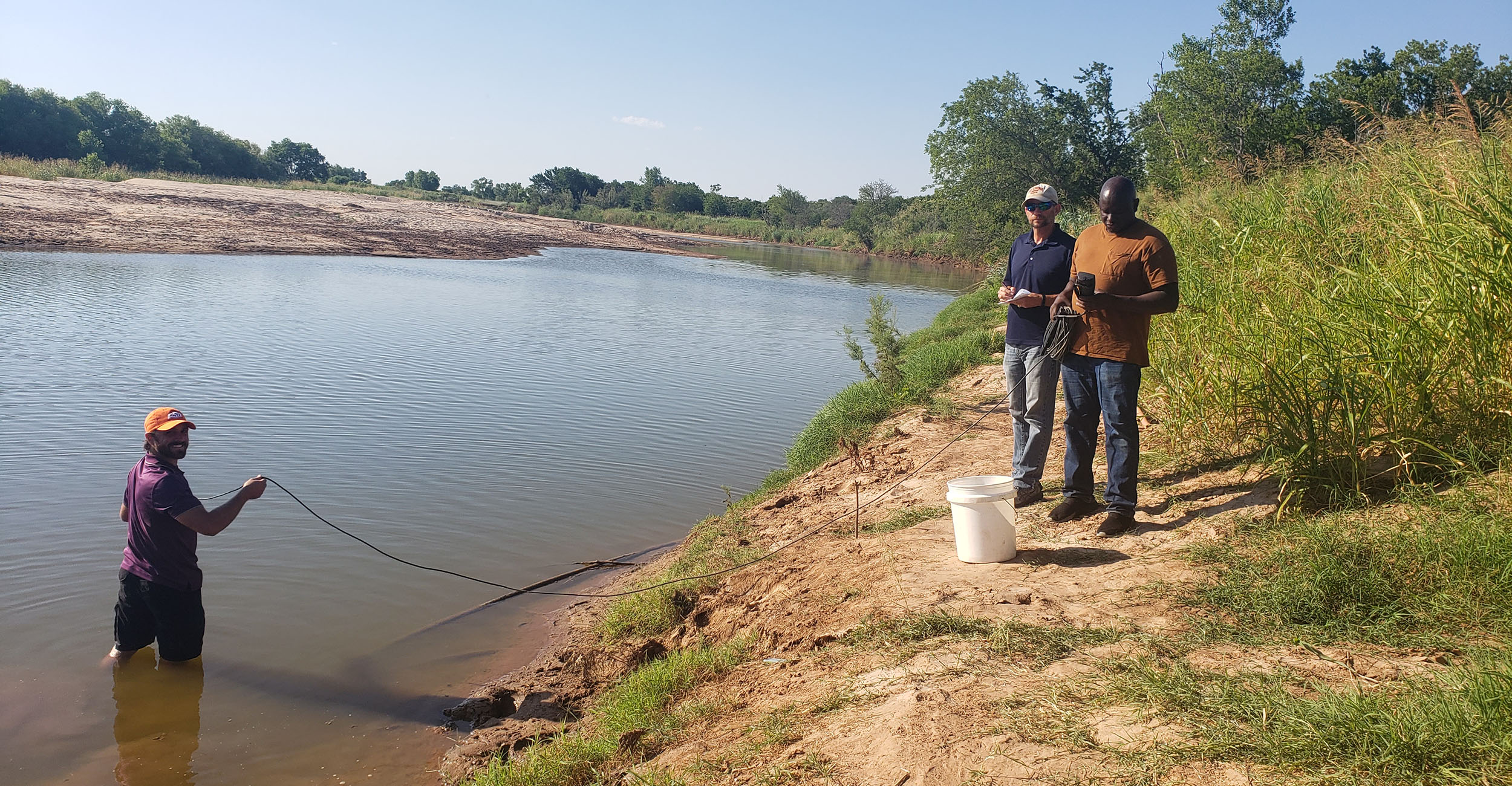 owrcprofile-main.jpg Two men stand on the edge of a creek. A third man wades in the creek. They are conducting reseach for the Oklahoma Water Resources Center.