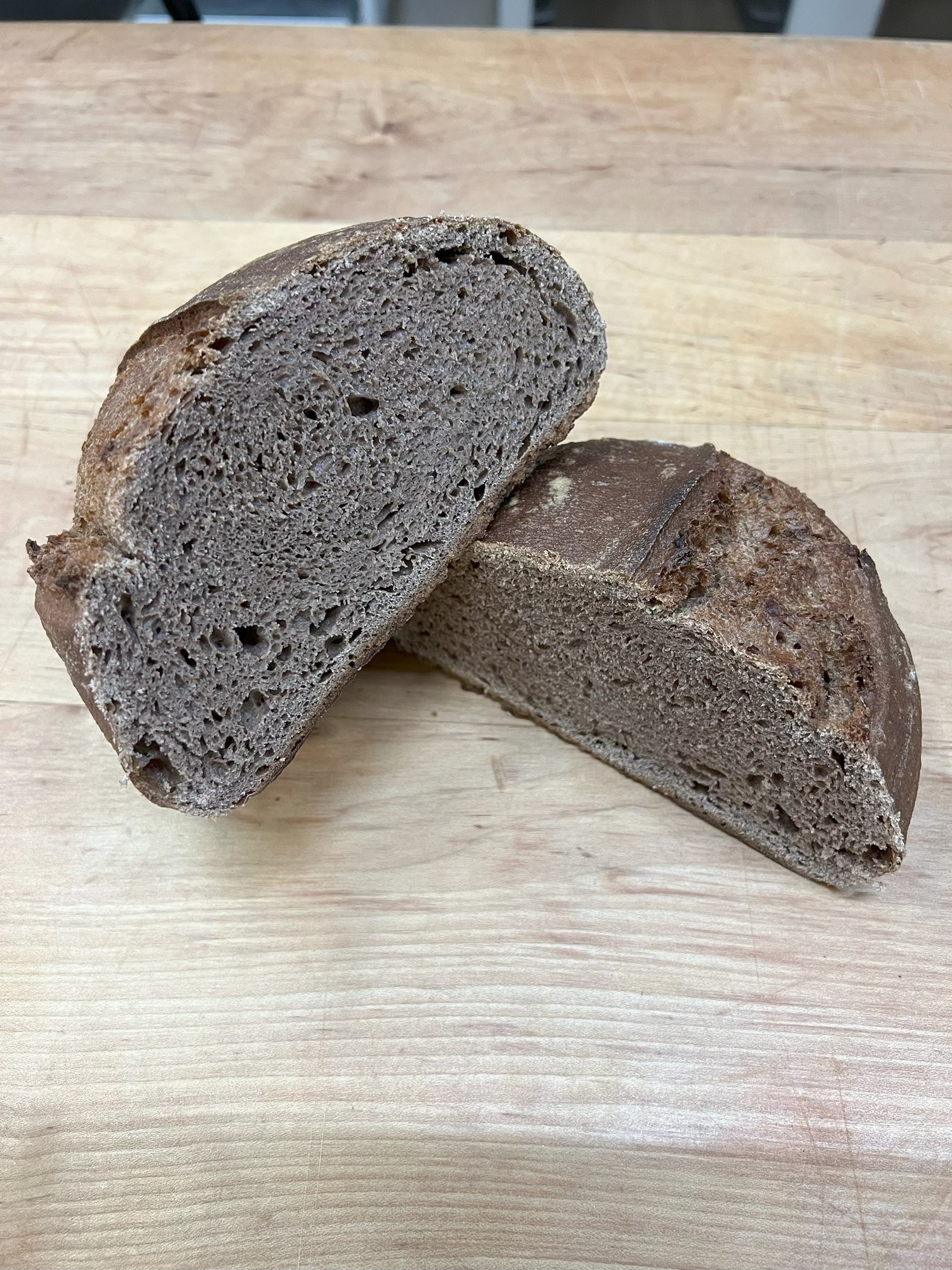 A loaf of bread is sliced in half with one piece displayed on top of the other showing the top and inside of the bread. A loaf of bread is sliced in half with one piece displayed on top of the other showing the top and inside of the bread.
